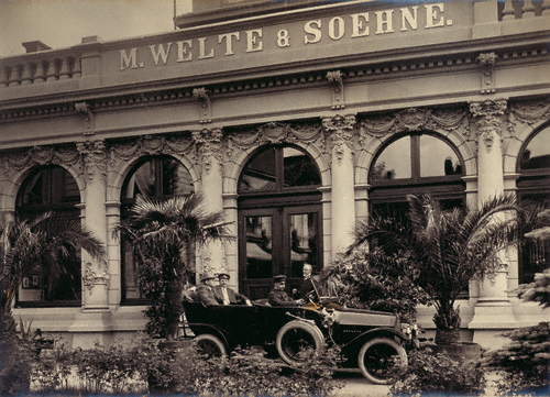 Reger im Auto vor dem Empfangsgebäude der Firma  zusammen mit Edwin und Berthold Welte, Freiburg i.Br. (1913). – Max-Reger-Institut, Karlsruhe.